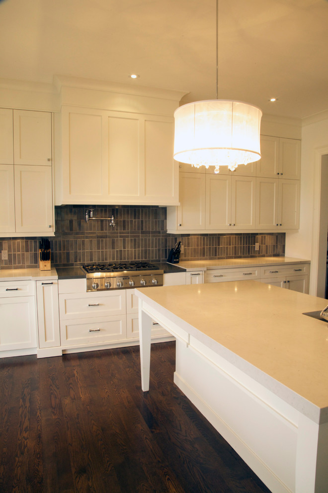 Large transitional l-shaped kitchen in Toronto with shaker cabinets, white cabinets, quartz benchtops, grey splashback, stainless steel appliances, dark hardwood floors and with island.
