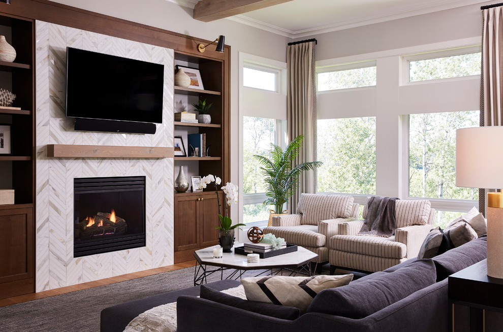 Inspiration for a large transitional open concept family room in Minneapolis with a standard fireplace, a tile fireplace surround, a wall-mounted tv, grey walls and light hardwood floors.