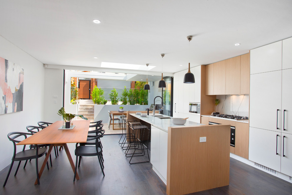 Design ideas for a contemporary open plan kitchen in Sydney with with island, an undermount sink, flat-panel cabinets, white cabinets, white splashback, dark hardwood floors, marble benchtops, stainless steel appliances, white benchtop and marble splashback.