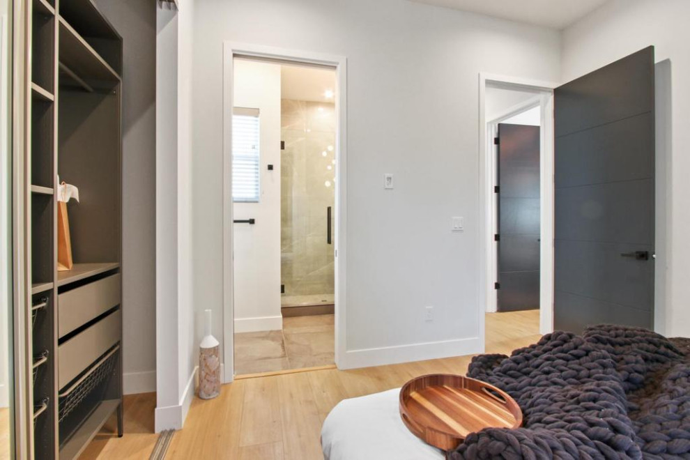 Foto de dormitorio principal contemporáneo de tamaño medio con paredes blancas, suelo de madera clara, suelo marrón, papel pintado y papel pintado