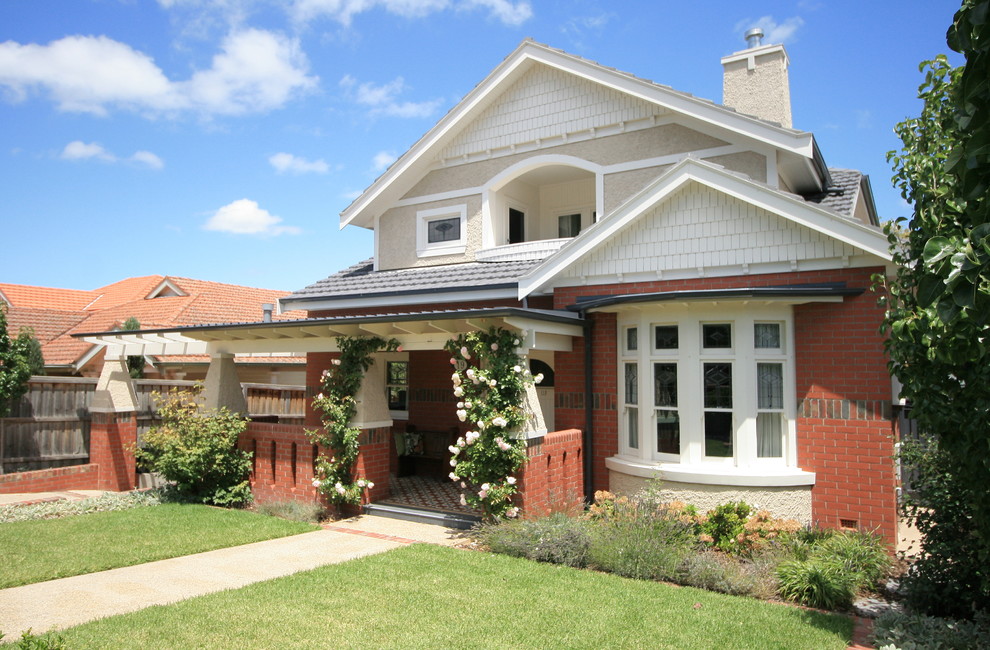 This is an example of an arts and crafts three-storey brick house exterior in Melbourne with a gable roof and a tile roof.