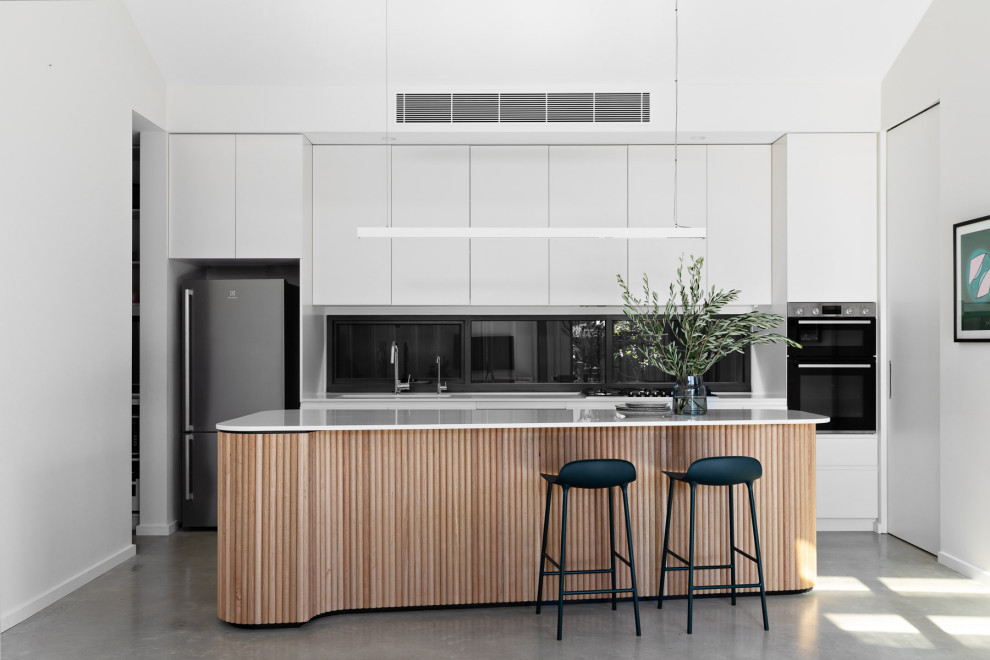 This is an example of a mid-sized modern galley eat-in kitchen in Sydney with an undermount sink, flat-panel cabinets, white cabinets, quartzite benchtops, window splashback, stainless steel appliances, concrete floors, with island, grey floor and white benchtop.