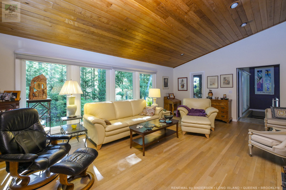 This is an example of a mid-sized contemporary enclosed living room in New York with purple walls, light hardwood floors, no fireplace, a freestanding tv, beige floor and timber.