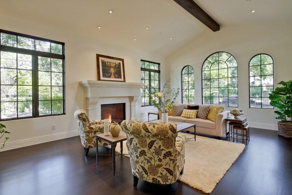 This is an example of a large mediterranean formal enclosed living room in San Francisco with white walls, dark hardwood floors, a standard fireplace, a stone fireplace surround, no tv and brown floor.