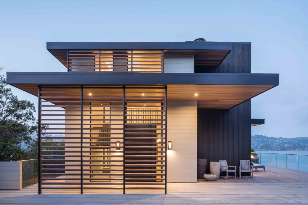 Inspiration pour une petite façade de maison noire design en bois à un étage avec un toit plat, un toit en métal et un toit gris.