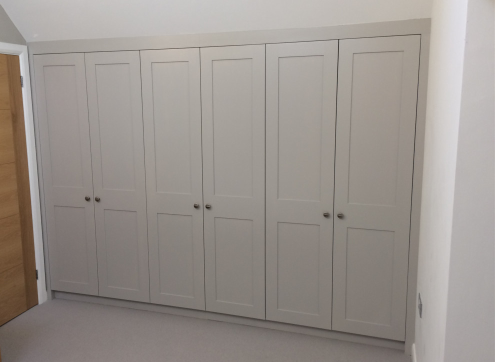 Inspiration for a medium sized contemporary built-in wardrobe in Buckinghamshire with shaker cabinets, white cabinets, carpet and beige floors.