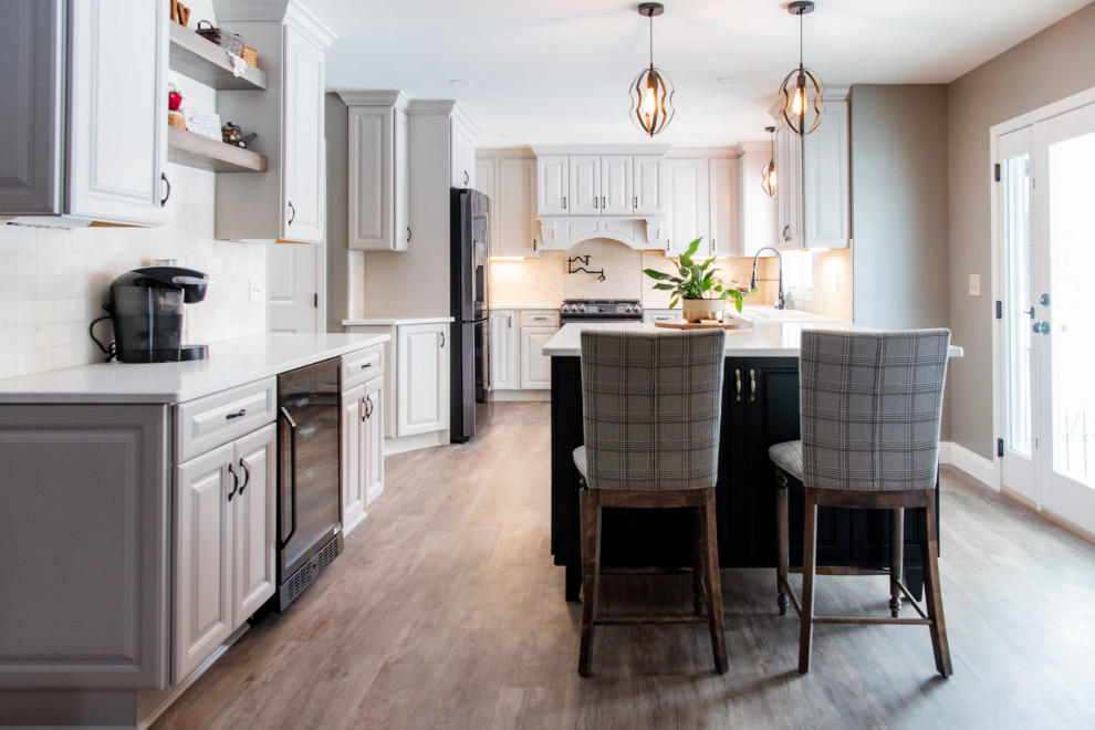 Foto på ett stort medelhavsstil vit kök, med en rustik diskho, luckor med upphöjd panel, svarta skåp, bänkskiva i kvarts, beige stänkskydd, stänkskydd i marmor, rostfria vitvaror, laminatgolv, en köksö och brunt golv