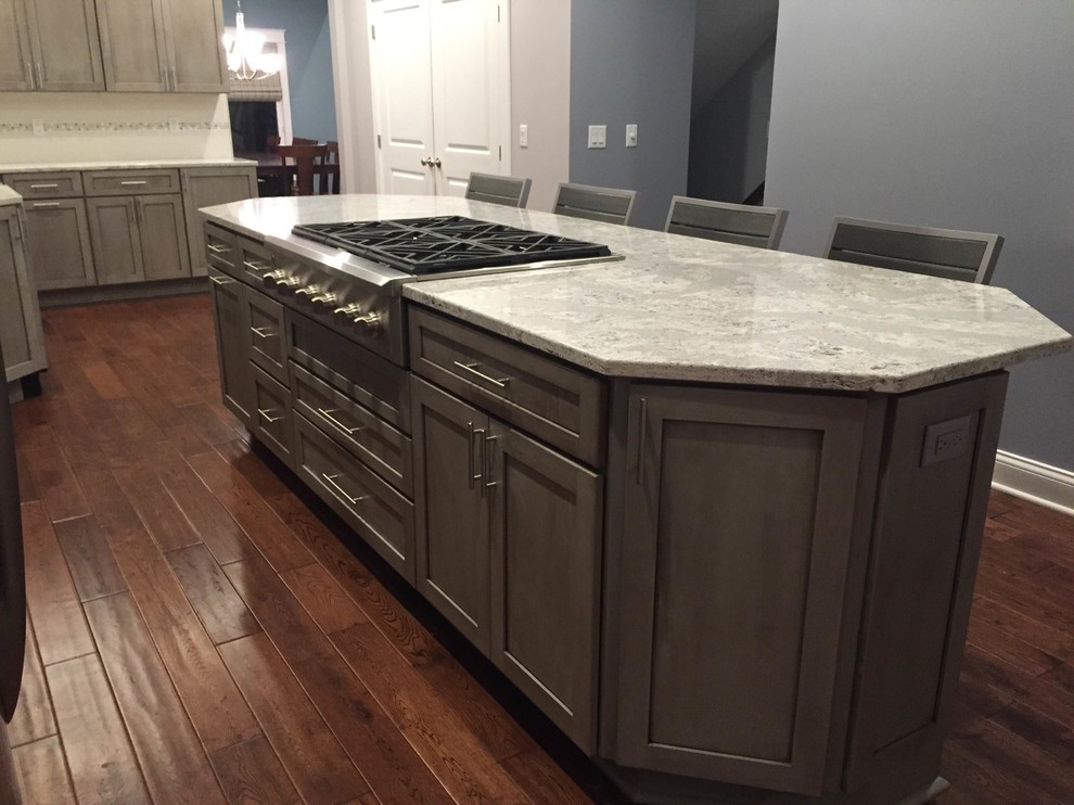 Inspiration for a large transitional l-shaped medium tone wood floor eat-in kitchen remodel in Grand Rapids with a farmhouse sink, shaker cabinets, gray cabinets, quartz countertops, white backsplash, porcelain backsplash, stainless steel appliances and an island