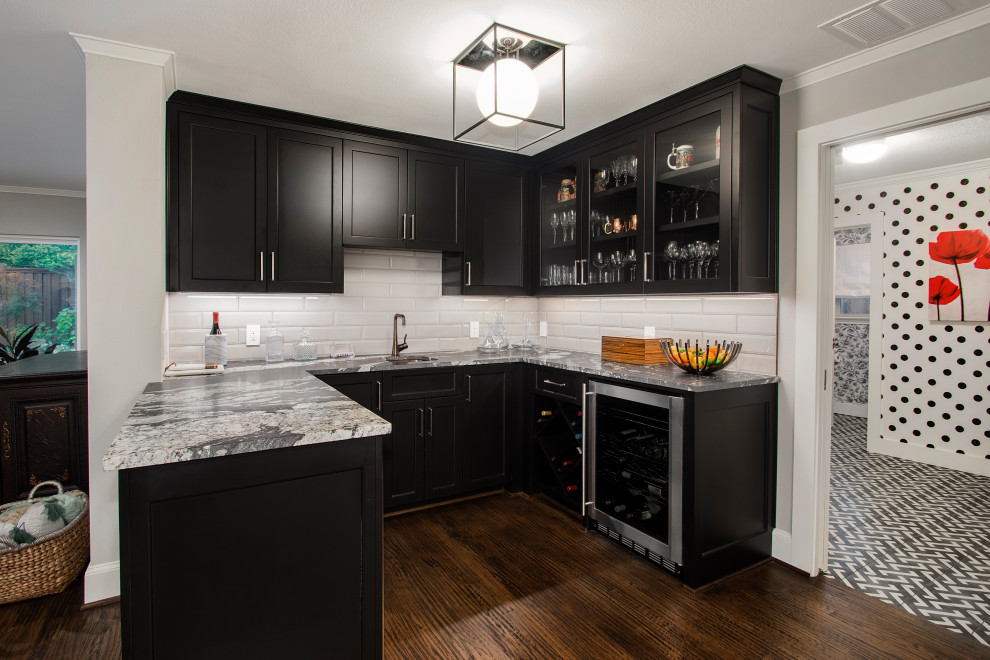Photo of a mid-sized transitional single-wall wet bar in Dallas with a drop-in sink, recessed-panel cabinets, black cabinets, quartz benchtops, white splashback, ceramic splashback, dark hardwood floors, brown floor and grey benchtop.