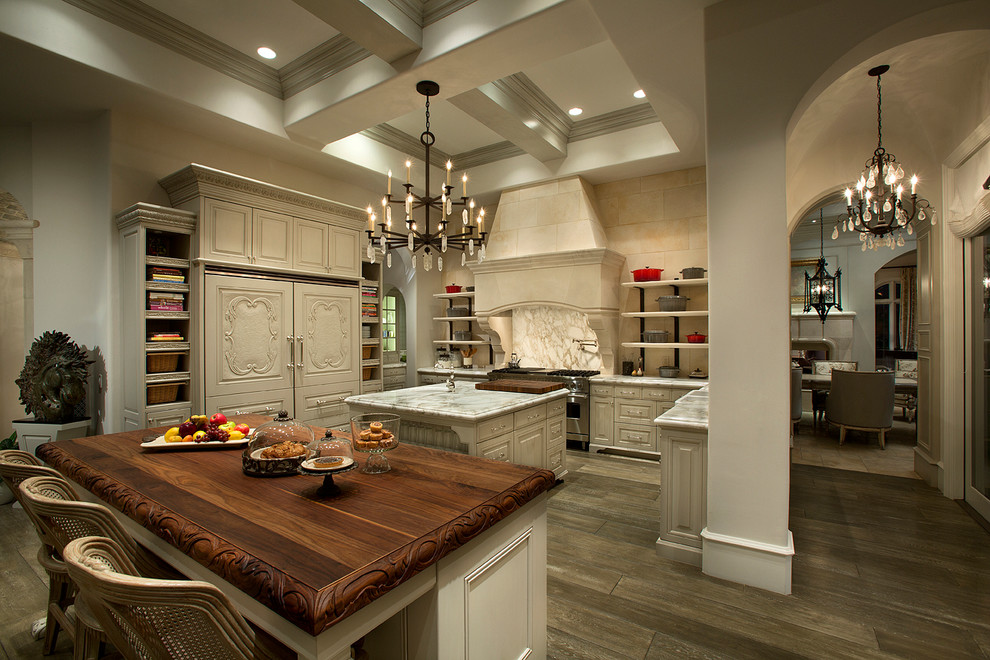 Large transitional u-shaped light wood floor, brown floor and coffered ceiling open concept kitchen photo in Phoenix with a drop-in sink, raised-panel cabinets, beige cabinets, marble countertops, beige backsplash, ceramic backsplash, stainless steel appliances, two islands and white countertops