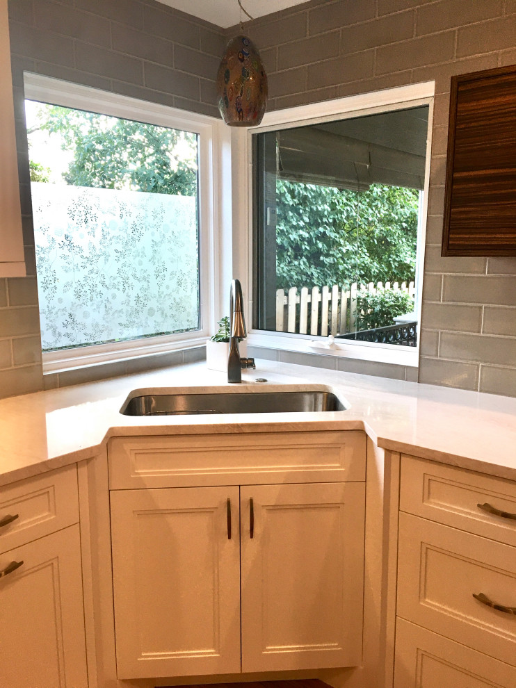 Small transitional u-shaped medium tone wood floor and brown floor enclosed kitchen photo in Denver with a drop-in sink, shaker cabinets, white cabinets, quartz countertops, gray backsplash, subway tile backsplash, stainless steel appliances, a peninsula and white countertops