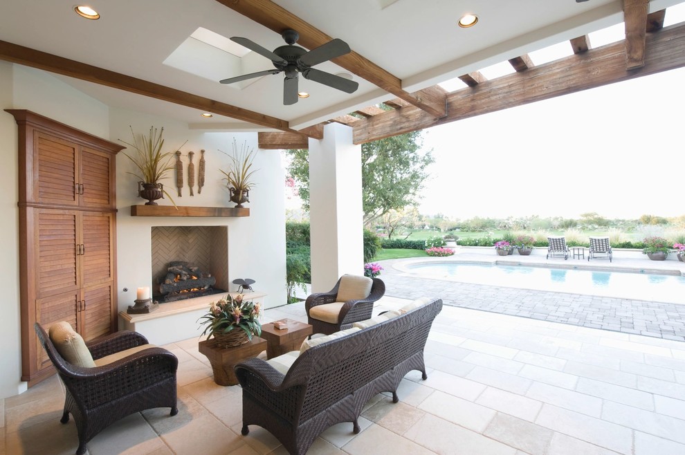 This is an example of a mid-sized mediterranean backyard patio in Miami with with fireplace, tile and a roof extension.
