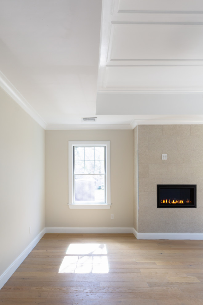 Inspiration for a large transitional master light wood floor, beige floor and tray ceiling bedroom remodel in Boston with beige walls, a standard fireplace and a tile fireplace