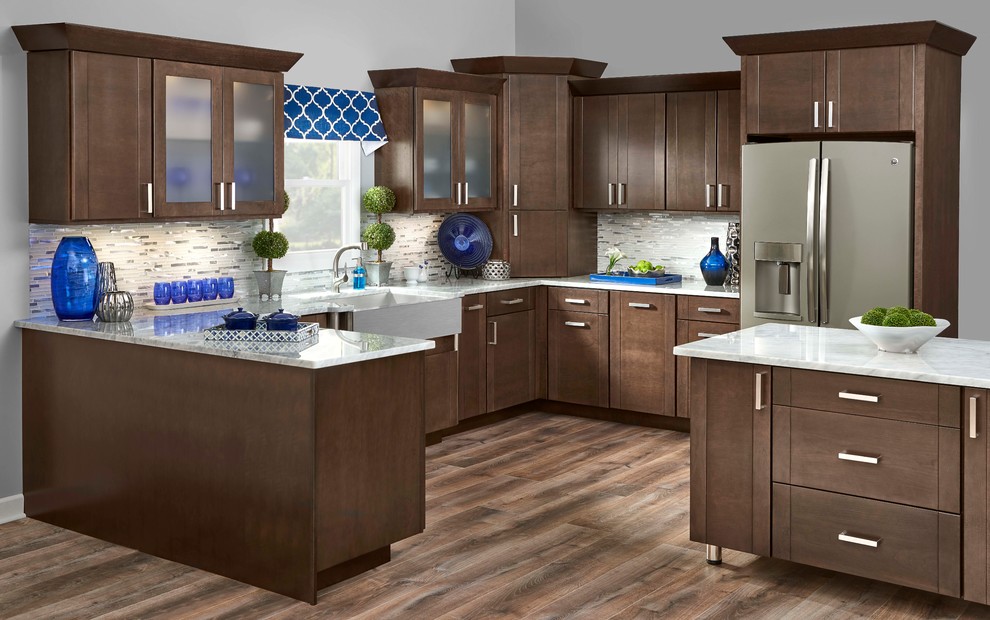 Mid-sized traditional l-shaped eat-in kitchen in Omaha with a farmhouse sink, shaker cabinets, brown cabinets, quartz benchtops, metallic splashback, matchstick tile splashback, stainless steel appliances, laminate floors and with island.