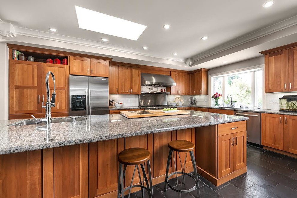 This is an example of a large modern u-shaped eat-in kitchen in San Francisco with a single-bowl sink, shaker cabinets, medium wood cabinets, granite benchtops, white splashback, ceramic splashback, stainless steel appliances, slate floors and with island.
