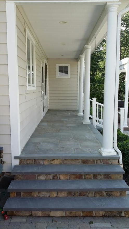 Mid-sized traditional front yard verandah in New York with natural stone pavers and a roof extension.