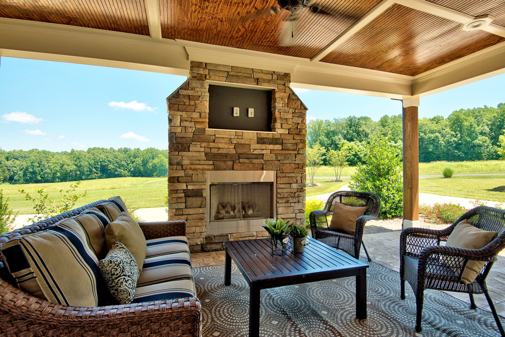 Inspiration for a country side yard patio in Raleigh with stamped concrete, a roof extension and with fireplace.