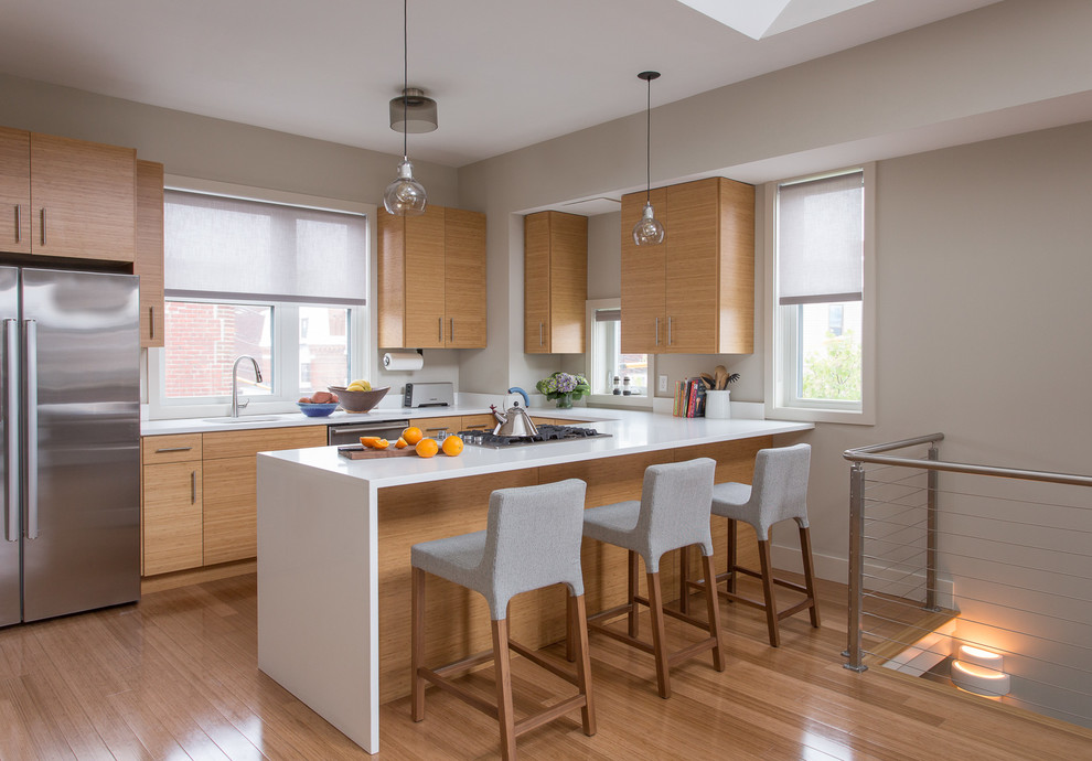 This is an example of a contemporary u-shaped kitchen in Boston with a single-bowl sink, flat-panel cabinets, light wood cabinets, stainless steel appliances, a peninsula and medium hardwood floors.