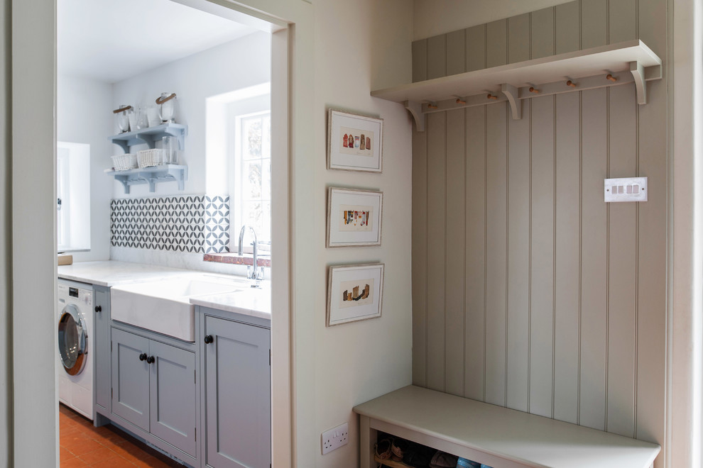 Inspiration for a small country galley dedicated laundry room in Kent with a farmhouse sink, granite benchtops, terra-cotta floors, a side-by-side washer and dryer, orange floor, beaded inset cabinets, blue cabinets, white walls and white benchtop.