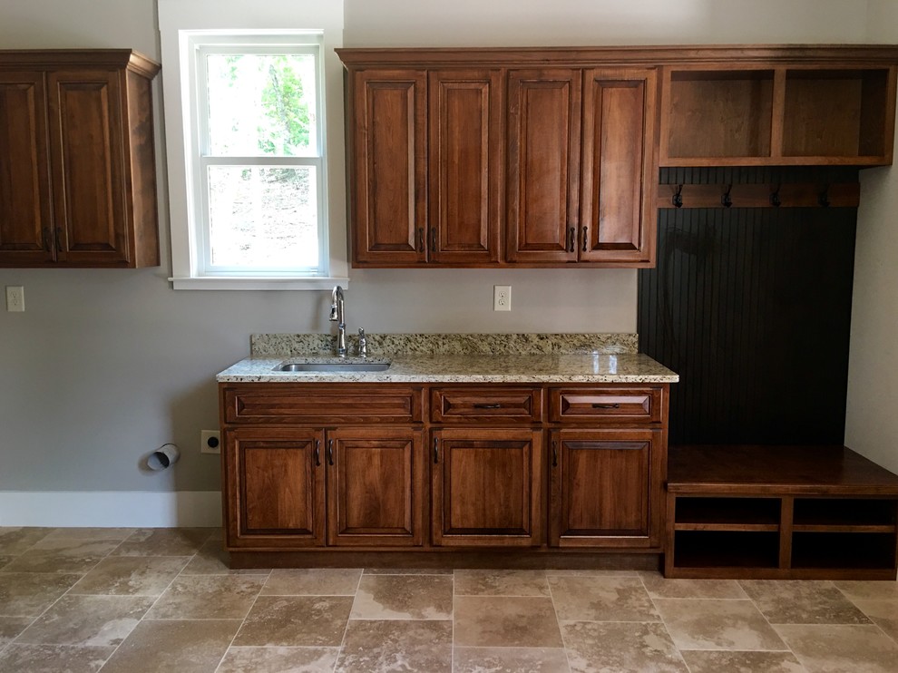 Photo of a large transitional single-wall laundry room in Atlanta with an undermount sink, raised-panel cabinets, medium wood cabinets, granite benchtops, grey walls and a side-by-side washer and dryer.