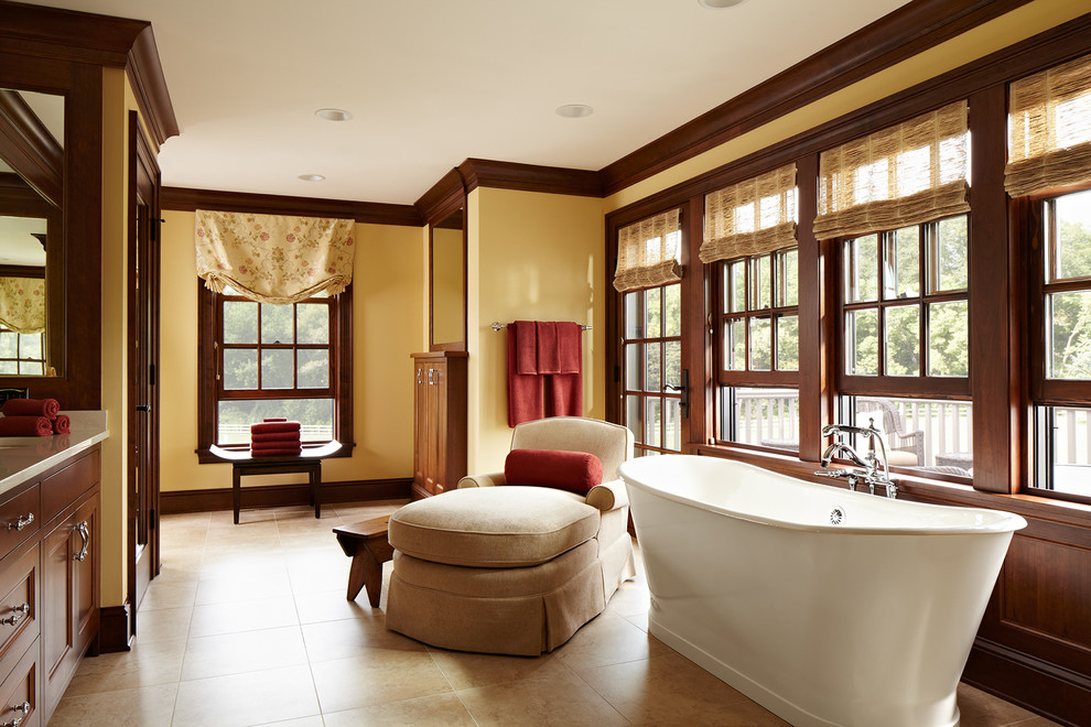 This is an example of an expansive country master bathroom in Minneapolis with recessed-panel cabinets, dark wood cabinets, a freestanding tub, yellow walls, porcelain floors, an undermount sink, marble benchtops, an alcove shower, beige tile and porcelain tile.