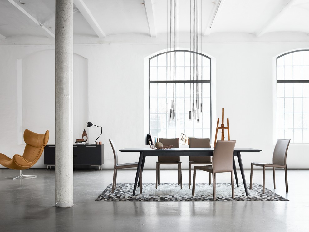 Scandinavian dining room in London with white walls and concrete floors.