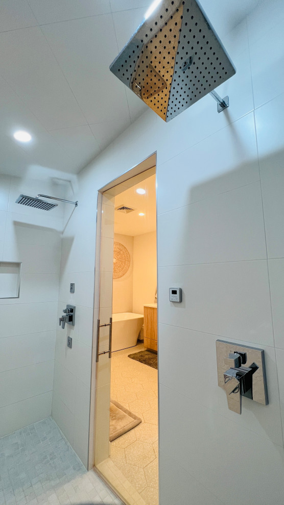 На фото: большая главная ванная комната в стиле модернизм с плоскими фасадами, фасадами цвета дерева среднего тона, отдельно стоящей ванной, душевой комнатой, писсуаром, желтой плиткой, керамической плиткой, бежевыми стенами, полом из керамогранита, врезной раковиной, столешницей из искусственного кварца, бежевым полом, душем с распашными дверями, белой столешницей, сиденьем для душа, тумбой под две раковины, встроенной тумбой, сводчатым потолком и обоями на стенах
