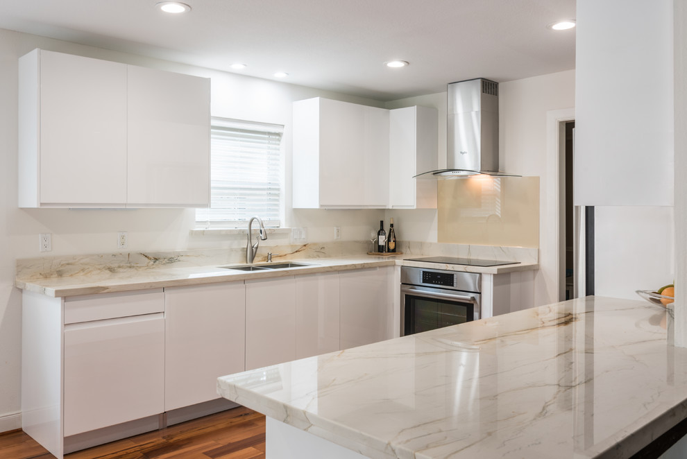 Mid-sized contemporary u-shaped eat-in kitchen in Houston with an undermount sink, flat-panel cabinets, white cabinets, quartzite benchtops, beige splashback, glass tile splashback, stainless steel appliances, light hardwood floors and no island.