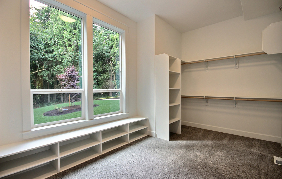 This is an example of an expansive arts and crafts gender-neutral walk-in wardrobe in Portland with open cabinets, white cabinets, carpet and beige floor.