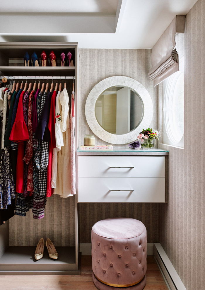 This is an example of a medium sized modern dressing room for women in Boston with flat-panel cabinets, white cabinets and medium hardwood flooring.