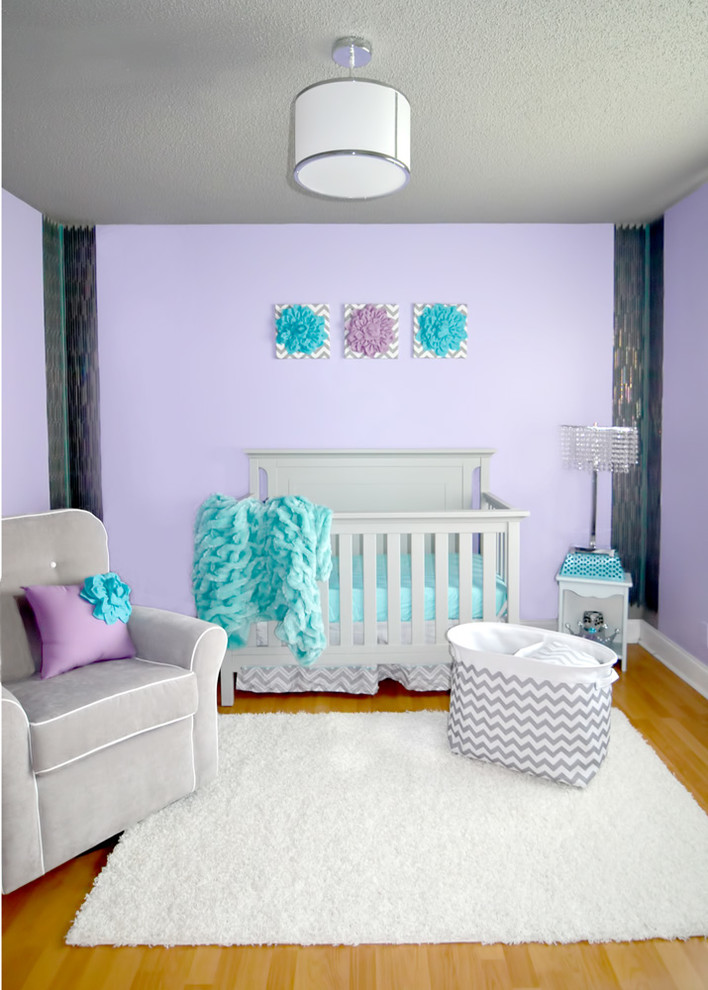 Inspiration for a mid-sized modern nursery for girls in Miami with purple walls and light hardwood floors.