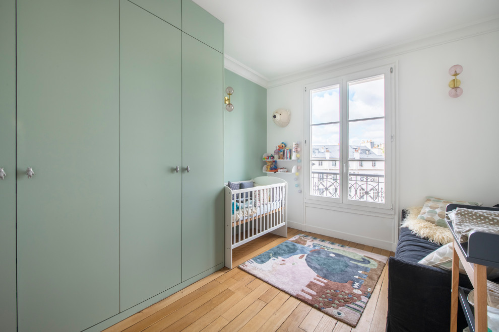 Inspiration pour une chambre de bébé neutre design de taille moyenne avec un mur multicolore, parquet clair et un sol beige.