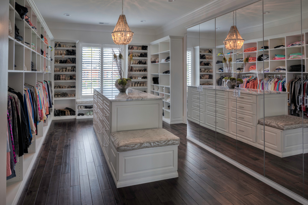 Large transitional gender-neutral walk-in wardrobe in Other with beaded inset cabinets, white cabinets and medium hardwood floors.