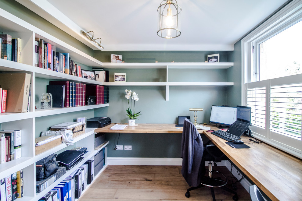 Ejemplo de despacho tradicional renovado de tamaño medio con paredes verdes, suelo de madera clara, escritorio empotrado y suelo beige