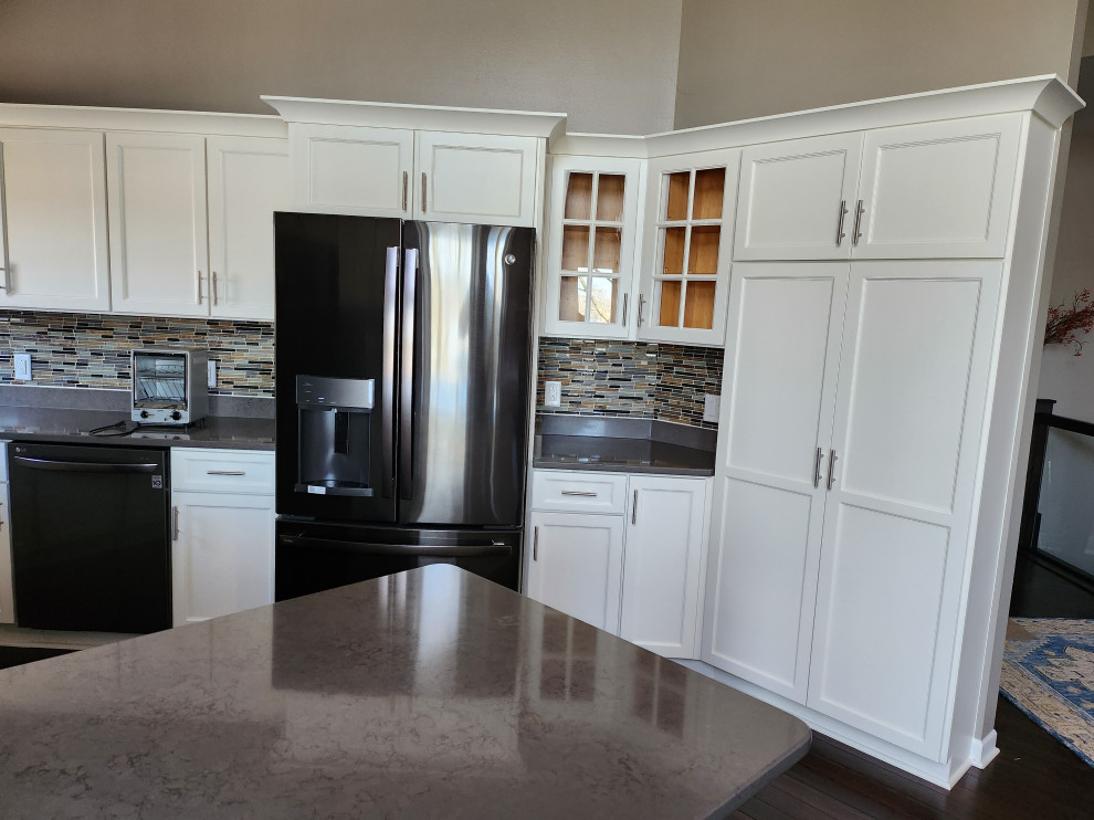 Inredning av ett klassiskt mellanstort grå grått kök, med en undermonterad diskho, skåp i shakerstil, gula skåp, bänkskiva i kvartsit, brunt stänkskydd, stänkskydd i glaskakel, rostfria vitvaror, mörkt trägolv, en halv köksö och brunt golv