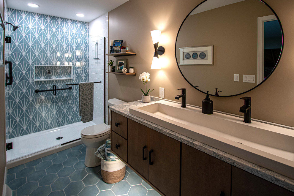 Photo of a mid-sized transitional 3/4 bathroom in Cleveland with furniture-like cabinets, brown cabinets, an alcove shower, a two-piece toilet, beige tile, porcelain tile, blue walls, porcelain floors, a trough sink, engineered quartz benchtops, blue floor, a hinged shower door, beige benchtops, a niche, a single vanity and a floating vanity.