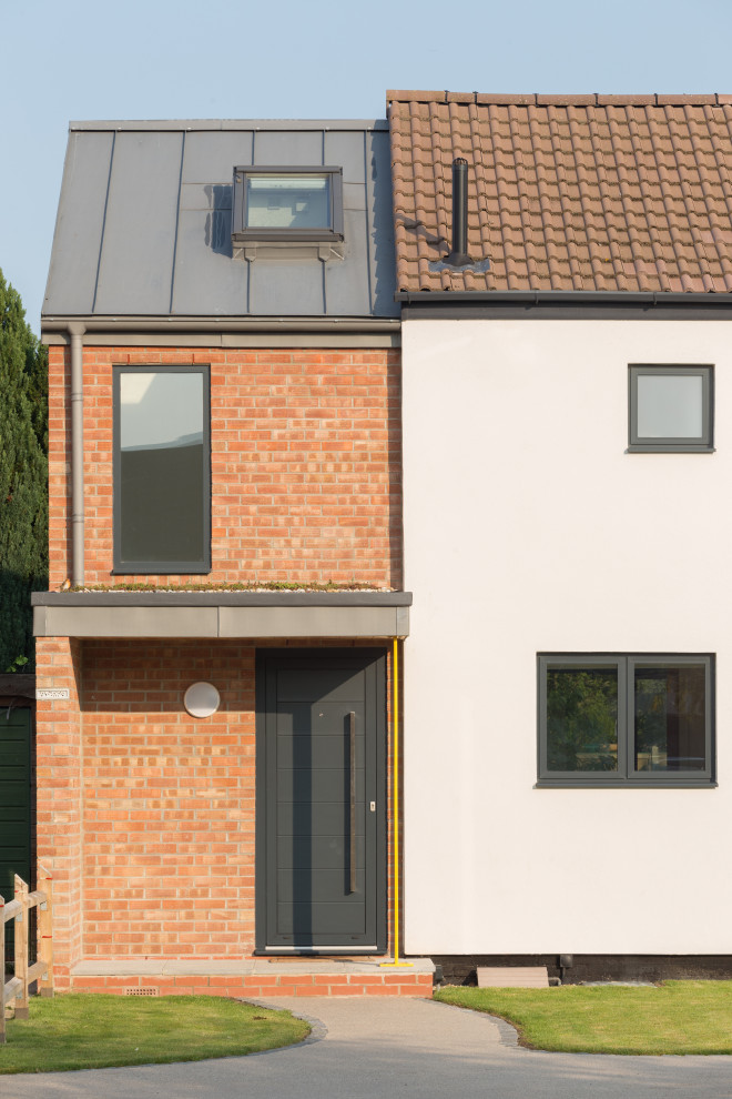 Inspiration for a mid-sized contemporary two-storey white duplex exterior in Cambridgeshire with mixed siding, a gable roof, a metal roof and a grey roof.