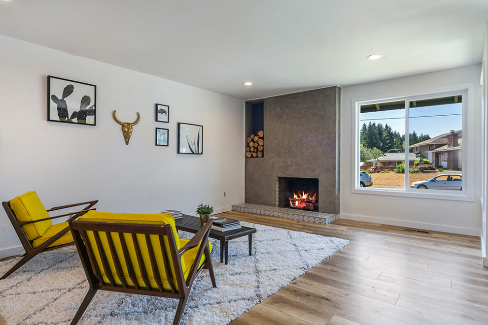 Large midcentury open concept living room in Seattle with white walls, laminate floors, a standard fireplace, a concrete fireplace surround and brown floor.