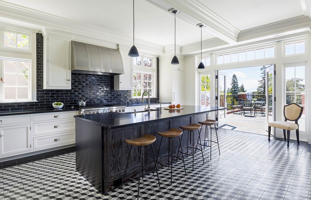 Design ideas for a traditional l-shaped kitchen in New York with a farmhouse sink, recessed-panel cabinets, white cabinets, black splashback, subway tile splashback, panelled appliances, porcelain floors, with island and multi-coloured floor.