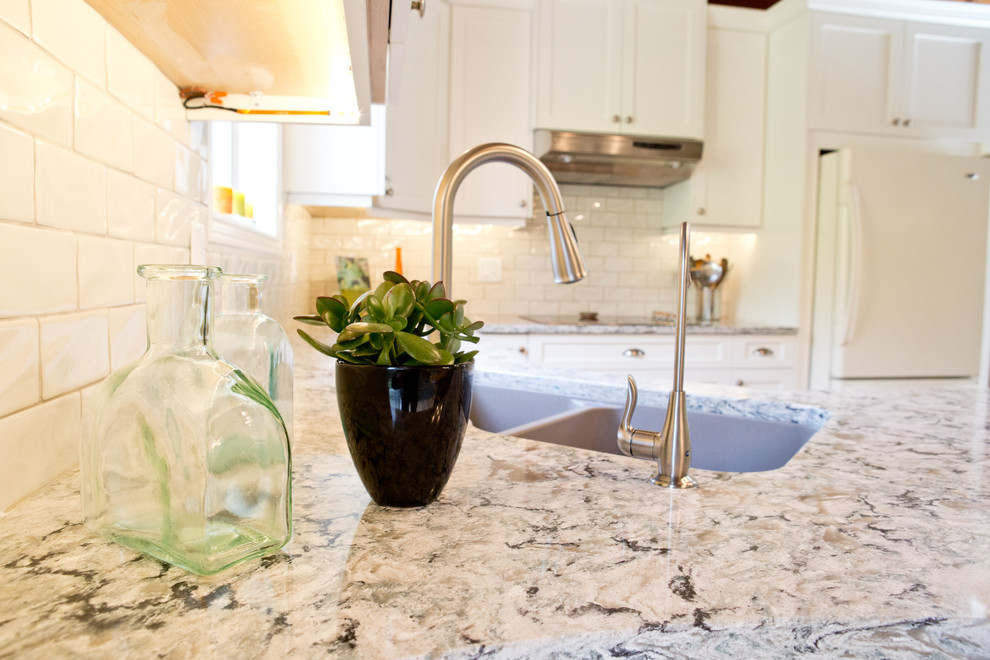 Inspiration for a mid-sized transitional u-shaped light wood floor kitchen remodel in Toronto with an undermount sink, shaker cabinets, white cabinets, granite countertops, white backsplash, subway tile backsplash, white appliances and a peninsula