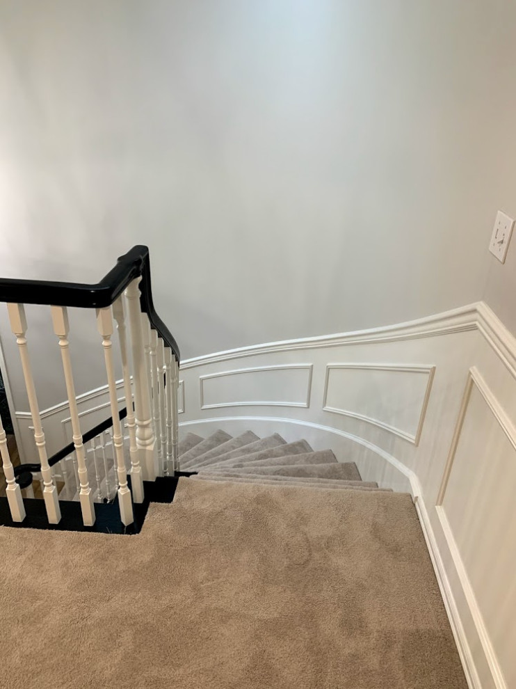 Mid-sized transitional carpeted curved staircase in Seattle with carpet risers, wood railing and decorative wall panelling.