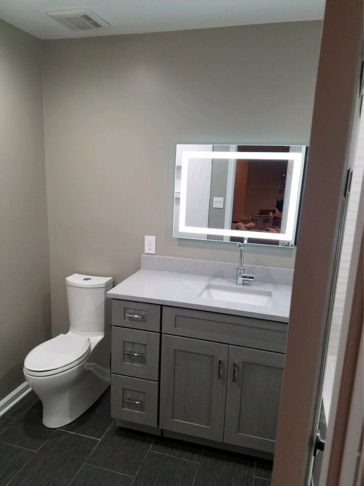 Mid-sized modern master bathroom in DC Metro with shaker cabinets, grey cabinets, an alcove tub, a shower/bathtub combo, a two-piece toilet, gray tile, porcelain tile, grey walls, porcelain floors, an undermount sink, quartzite benchtops, grey floor, an open shower, grey benchtops, a niche, a single vanity and a built-in vanity.