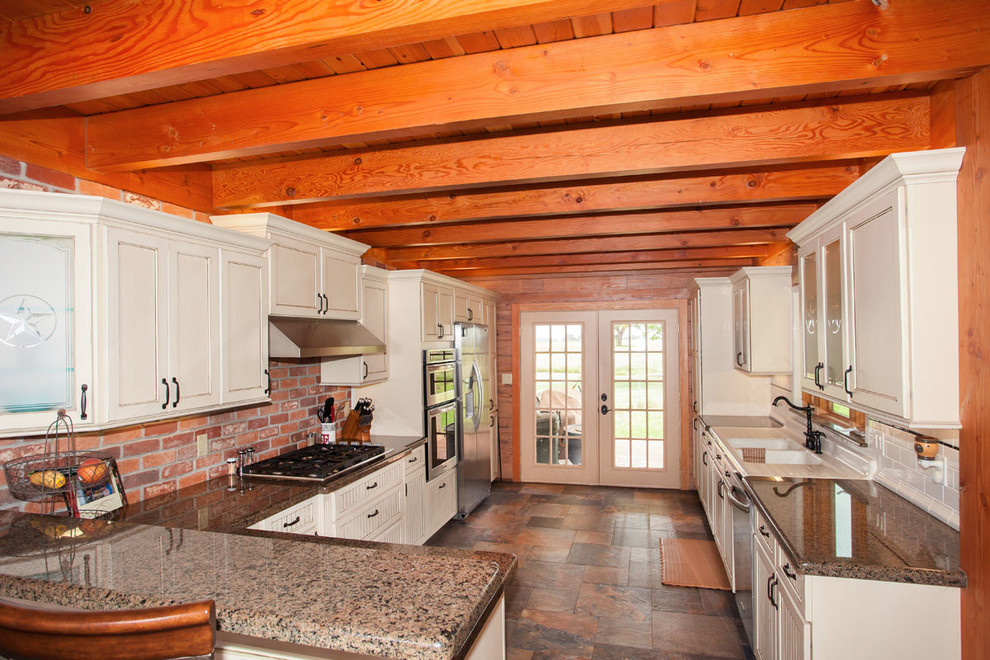 Eat-in kitchen - large rustic eat-in kitchen idea in Austin with a double-bowl sink, raised-panel cabinets, white cabinets, red backsplash, stainless steel appliances and a peninsula