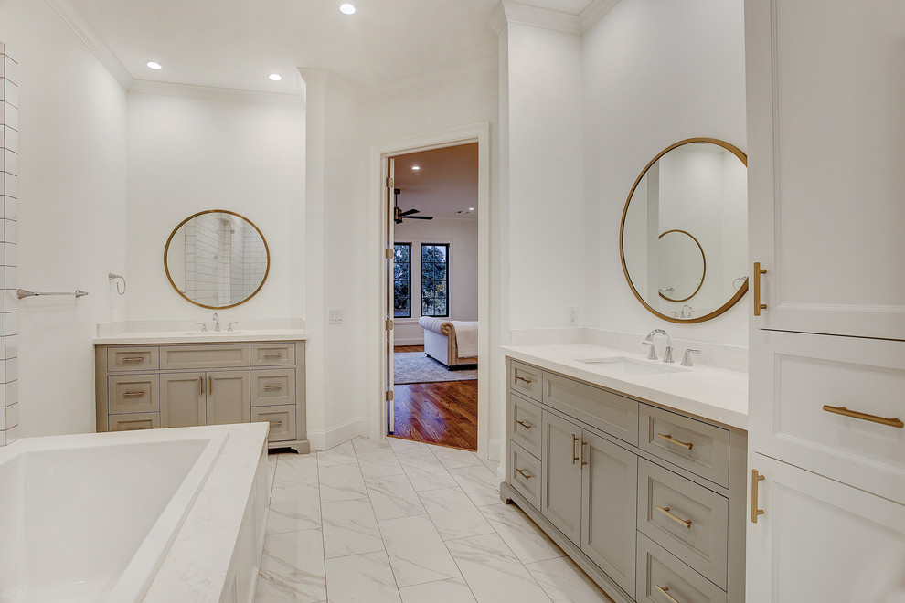 Large traditional master bathroom in Houston with furniture-like cabinets, grey cabinets, a drop-in tub, a corner shower, a two-piece toilet, white tile, ceramic tile, white walls, porcelain floors, an undermount sink, engineered quartz benchtops, white floor, a hinged shower door and white benchtops.