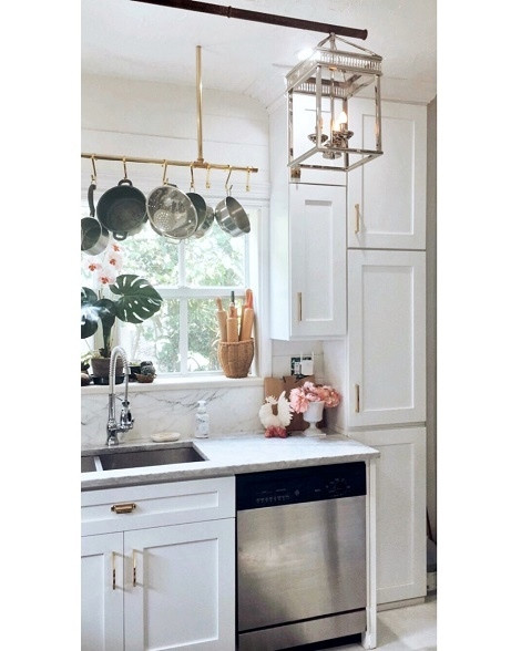 Small laminate floor and white floor enclosed kitchen photo with a drop-in sink, shaker cabinets, white cabinets, marble countertops, white backsplash, marble backsplash, stainless steel appliances and no island