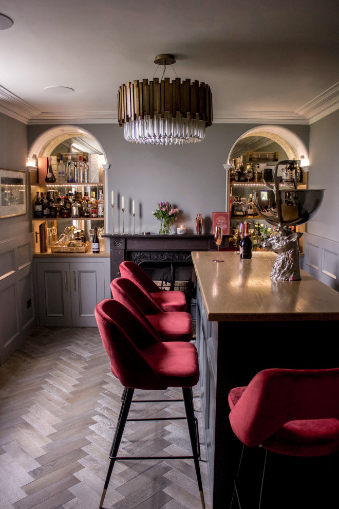 Mid-sized eclectic home bar in West Midlands with no sink, black cabinets, wood benchtops, mirror splashback, painted wood floors and grey floor.