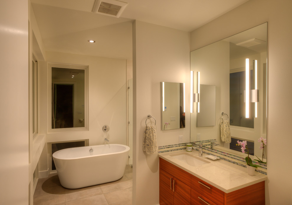 Mid-sized modern master bathroom in Seattle with flat-panel cabinets, brown cabinets, a freestanding tub, an open shower, a one-piece toilet, white tile, ceramic tile, white walls, porcelain floors, an undermount sink, solid surface benchtops, beige floor, an open shower and white benchtops.