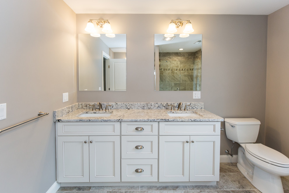 Inspiration for a large transitional master bathroom in Providence with shaker cabinets, white cabinets, an alcove shower, a two-piece toilet, gray tile, porcelain tile, beige walls, porcelain floors, an undermount sink, granite benchtops and a hinged shower door.