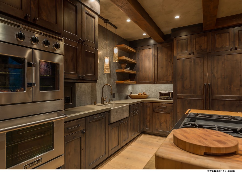 Mid-sized mountain style l-shaped light wood floor kitchen photo with an undermount sink, shaker cabinets, dark wood cabinets, stainless steel appliances and an island