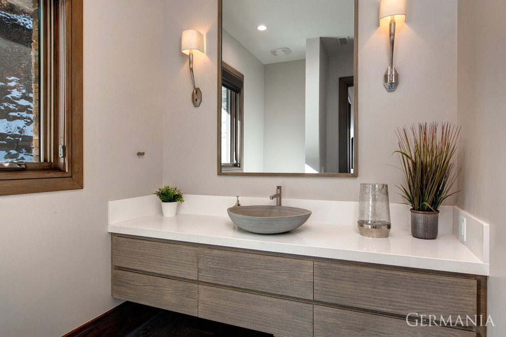 Cette image montre une salle de bain minimaliste en bois clair avec un placard à porte plane, un mur beige, un plan de toilette blanc, meuble simple vasque et meuble-lavabo suspendu.